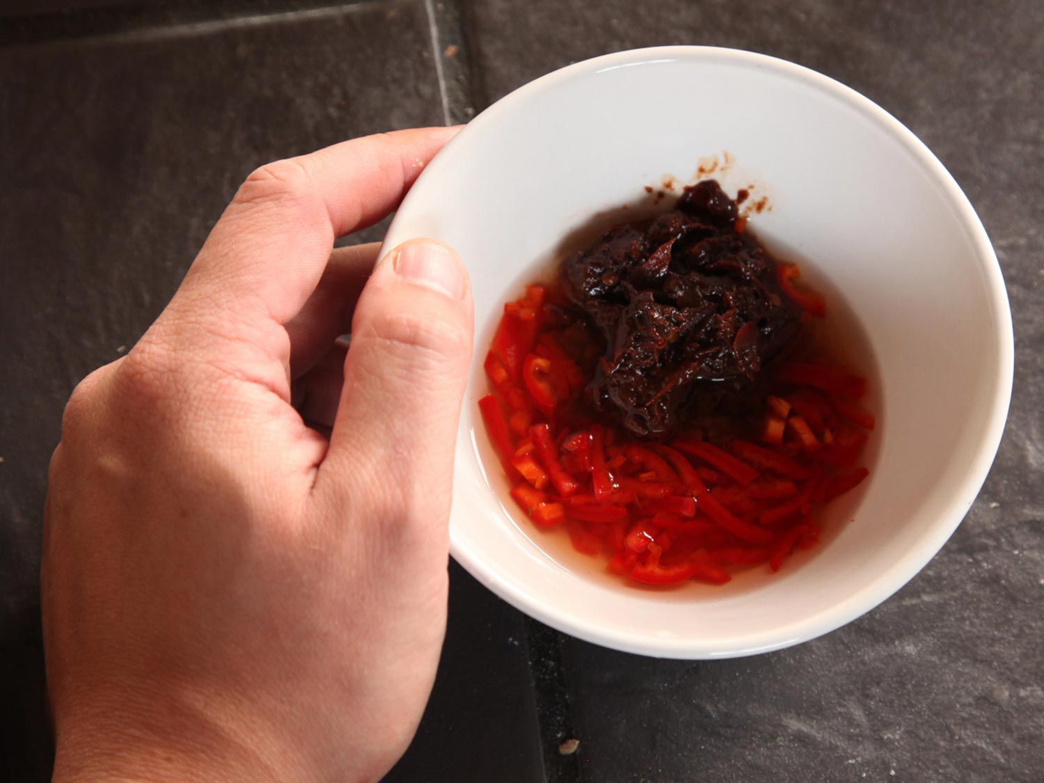 A prep bowl containing pickled red chile slices and Sichuan chile-bean paste.