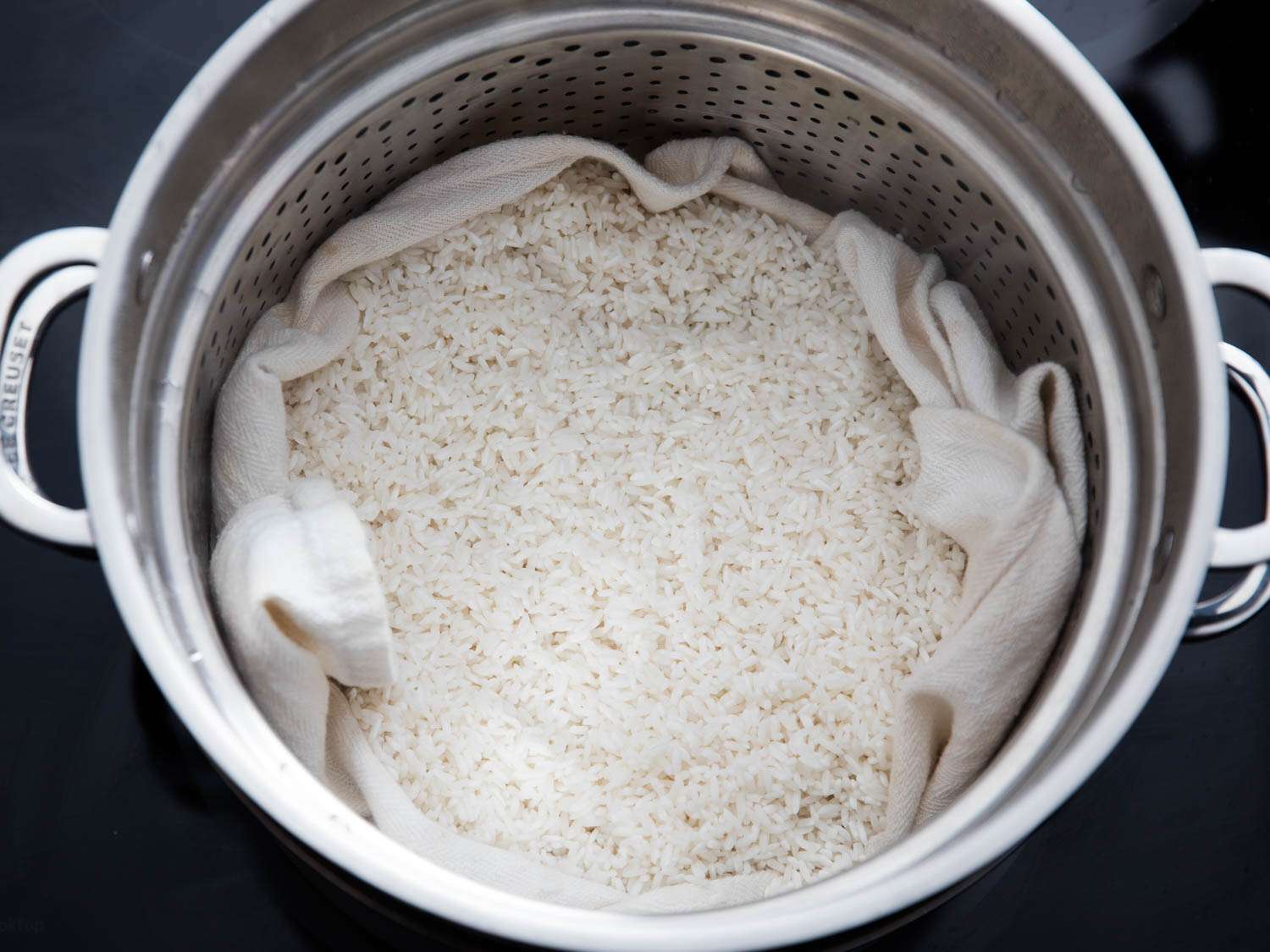 Sticky rice being cooked on a cloth in a steamer. 