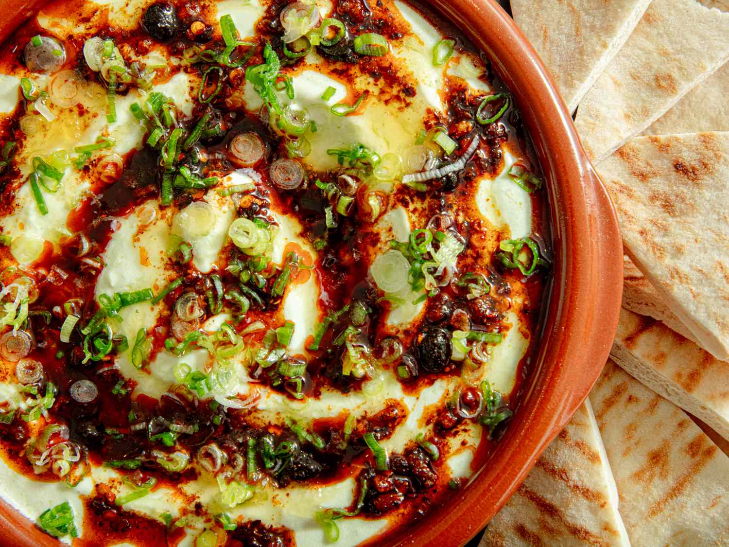 Labneh dip garnished with scallions and spices served with pita bread