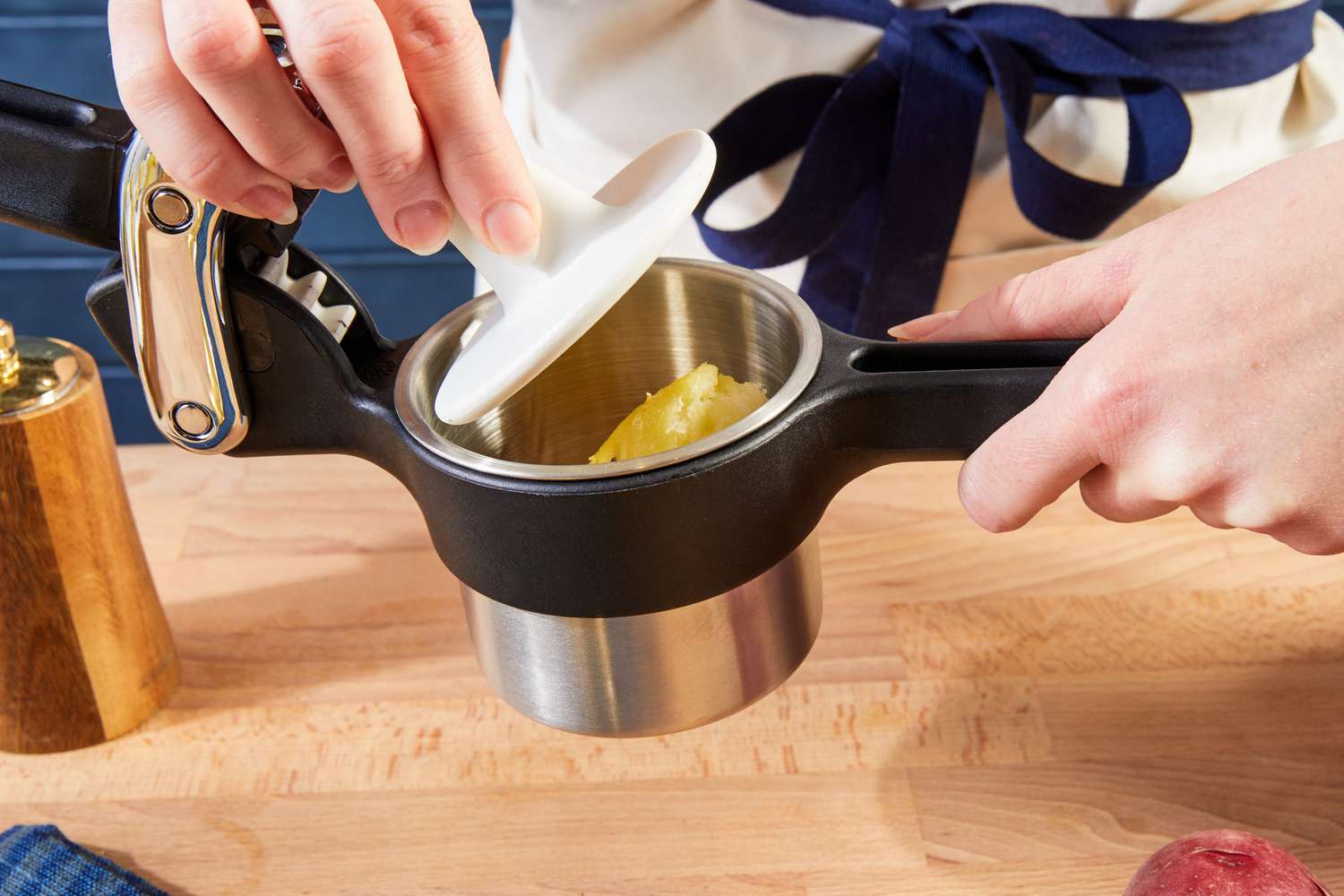 A person using the Chef'n potato ricer to rice a peeled, cooked potato.