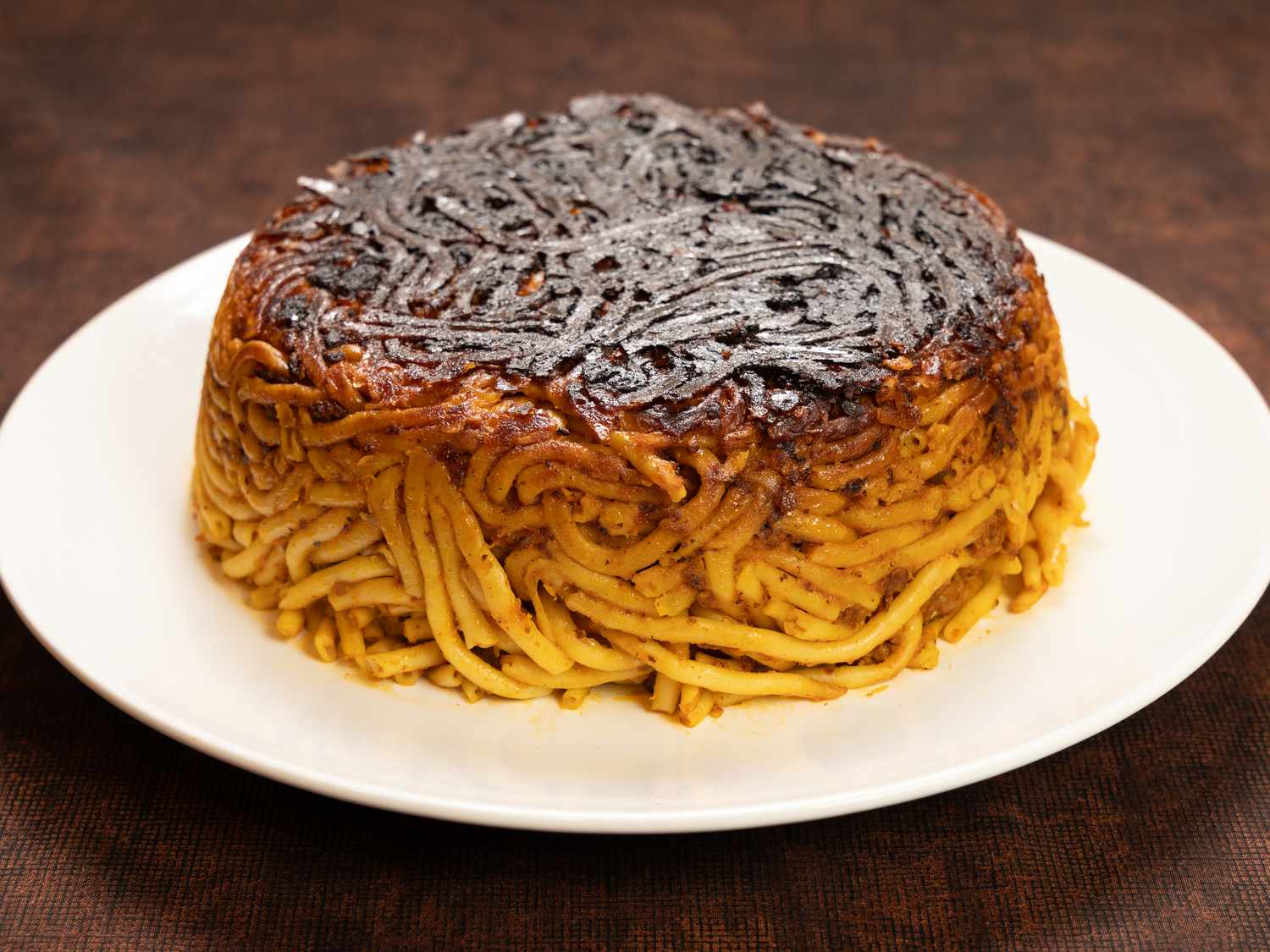 Plate of tahdig macaroni displayed on a brown table surface
