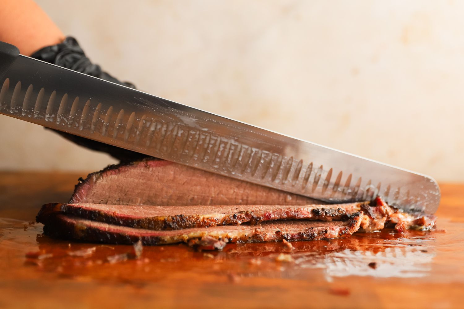 A person slicing meat using the Victorinox Fibrox Pro Slicing Knife