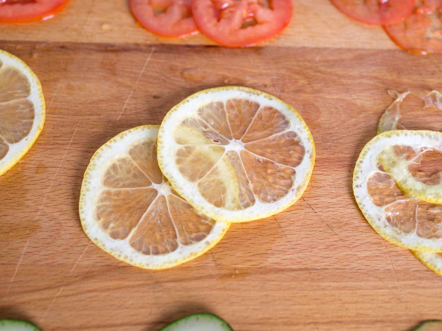 Close-up of lemon slices cut in three different thicknesses on a wood surface