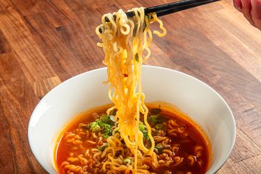 Chopsticks lifting noodles out of a bowl of soup