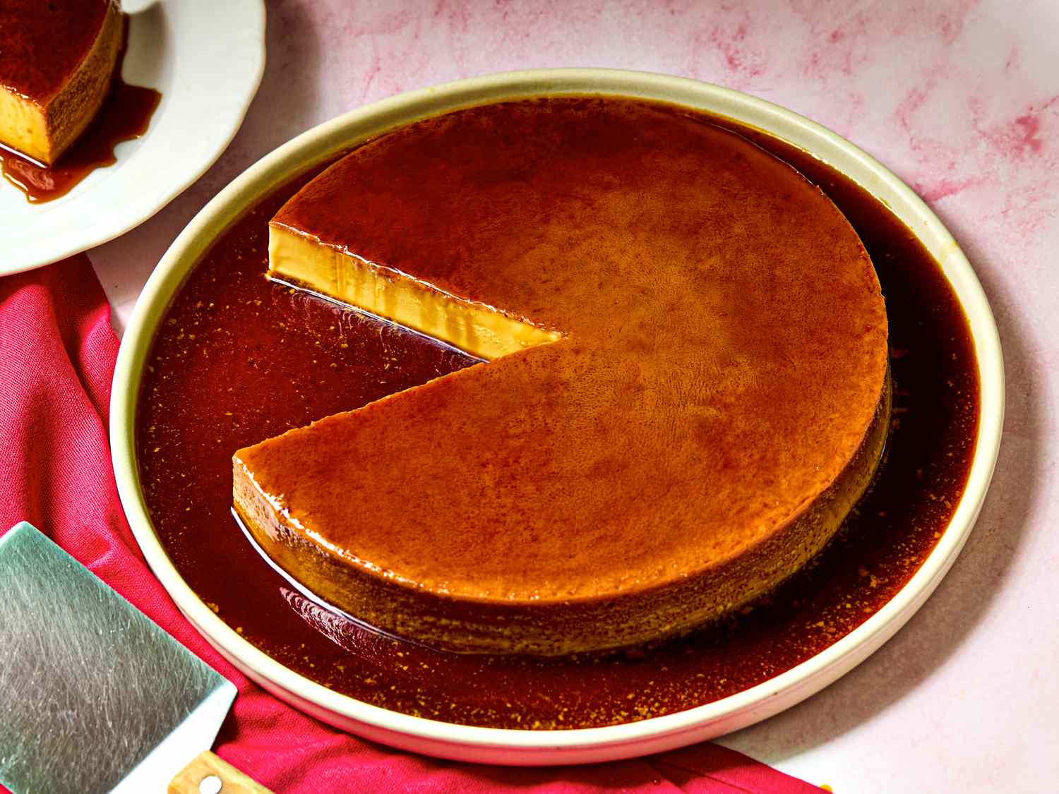 A caramel flan dessert with a slice removed on a plate with sauce
