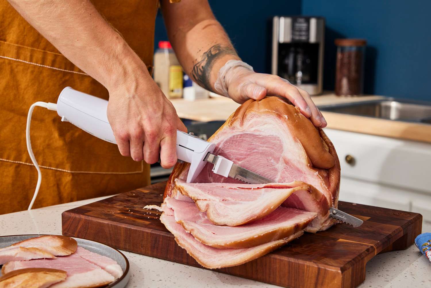 a person holding the hamilton beach electric knife and cutting slices of ham