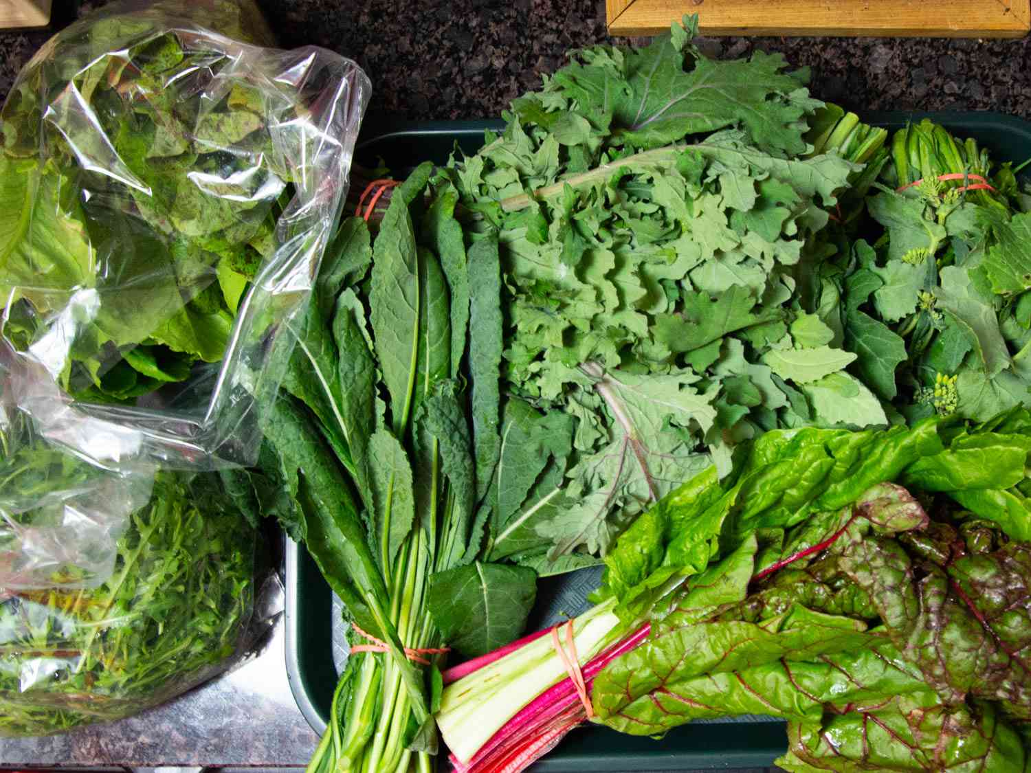 Overhead of bunches of hearty greens that need to be put away.