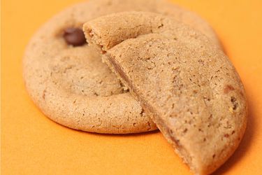 Closeup of mock batch cookies. One has been cut in half to show the soft interior.