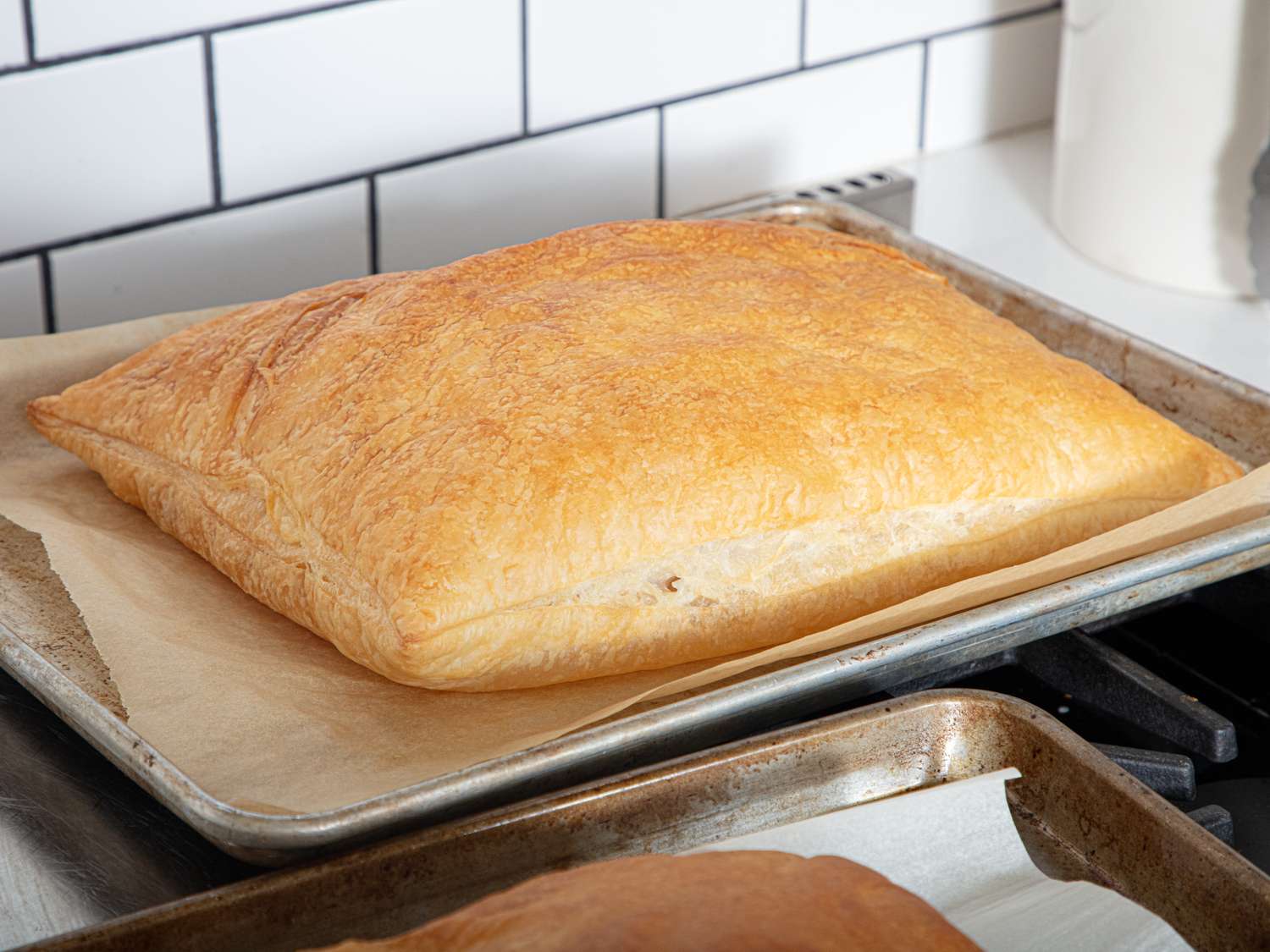A baked puff pastry resting on a baking sheet lined with parchment paper on a kitchen counter
