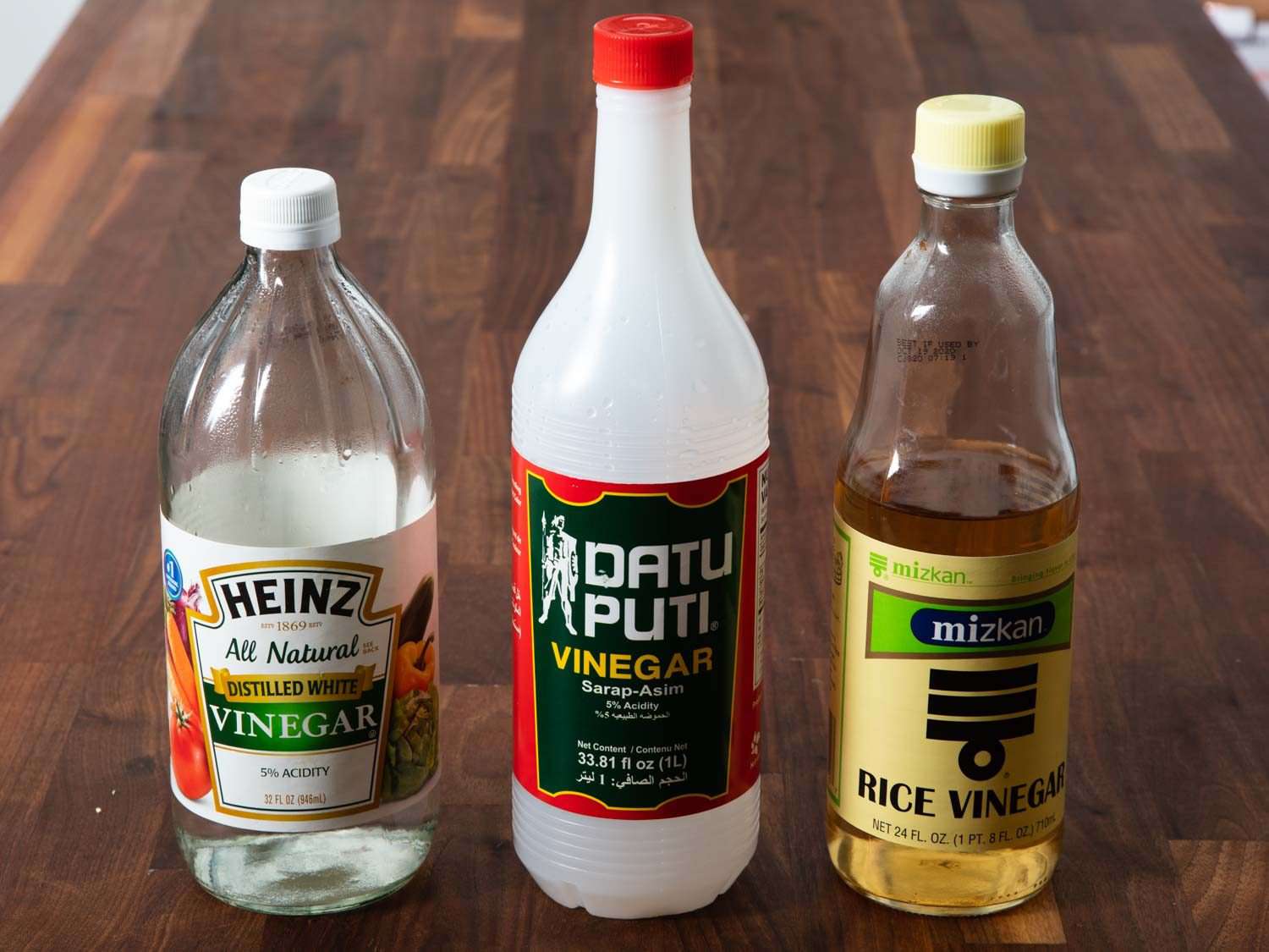 Three bottles of vinegar, from left to right: Heinz distilled white vinegar, Datu Puti distilled cane vinegar, Mizkan rice vinegar