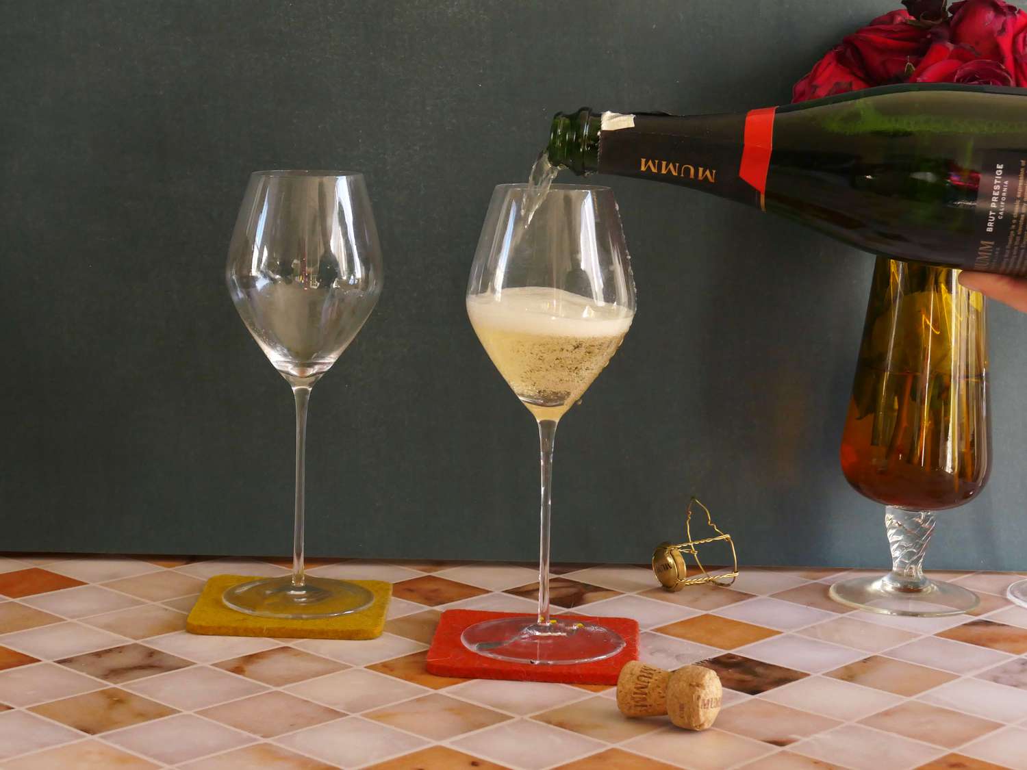 a person pouring champagne into the glas vin tulip glasses.