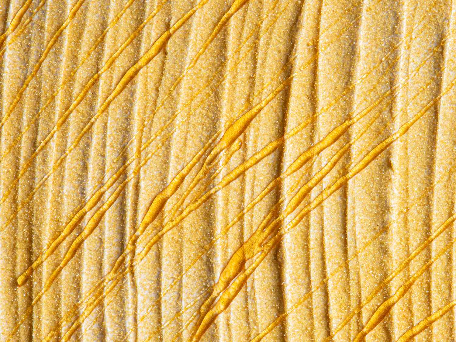 Drizzled honey on a textured golden surface showing the honeys viscosity and sheen