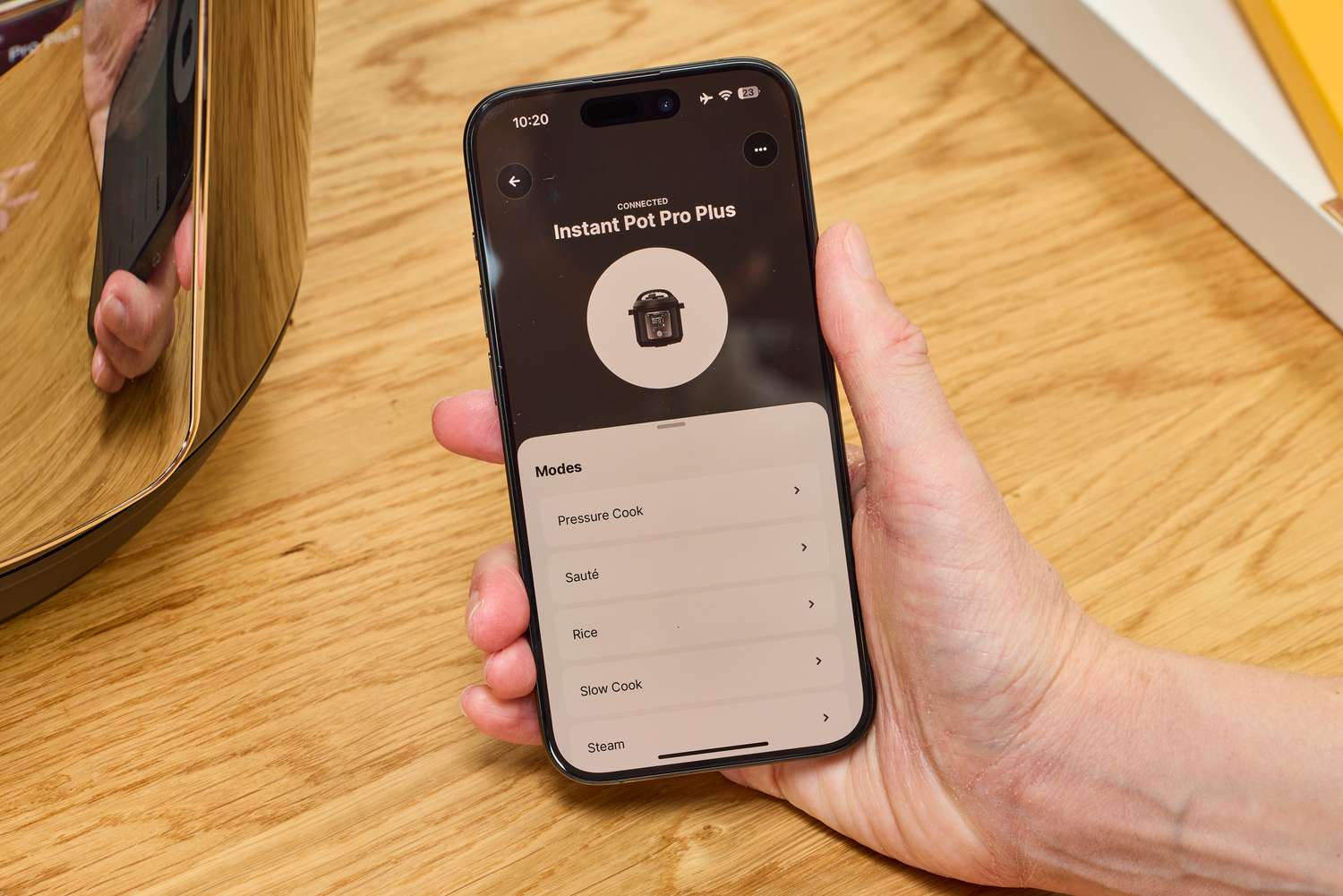 A person controls the Instant Pot Pro Plus Wi-Fi Smart 10-in-1 6-Quart Pressure Cooker with their smartphone