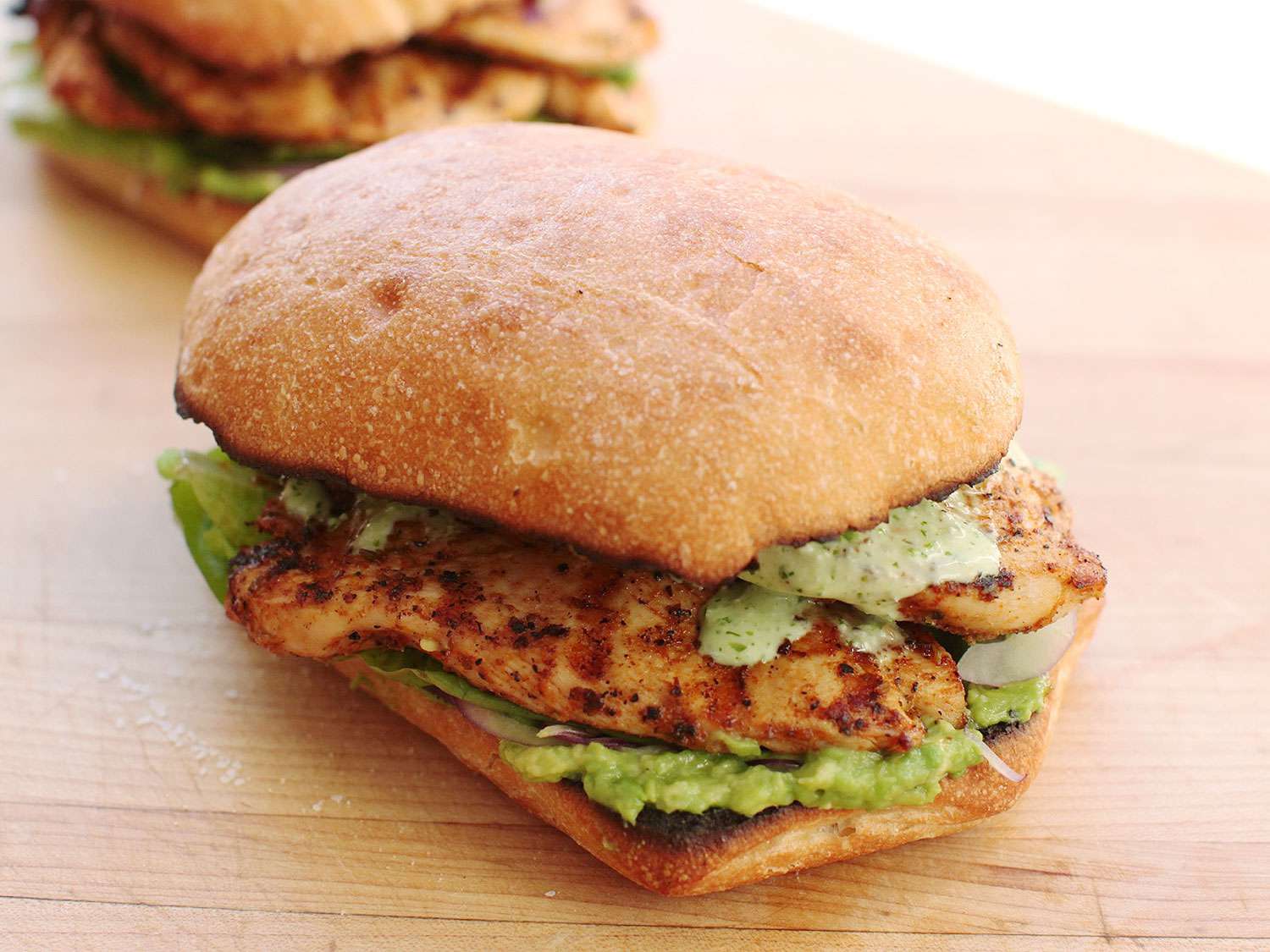 Finished Peruvian grilled-chicken sandwich, with green sauce, avocado, red onion, and romaine lettuce.