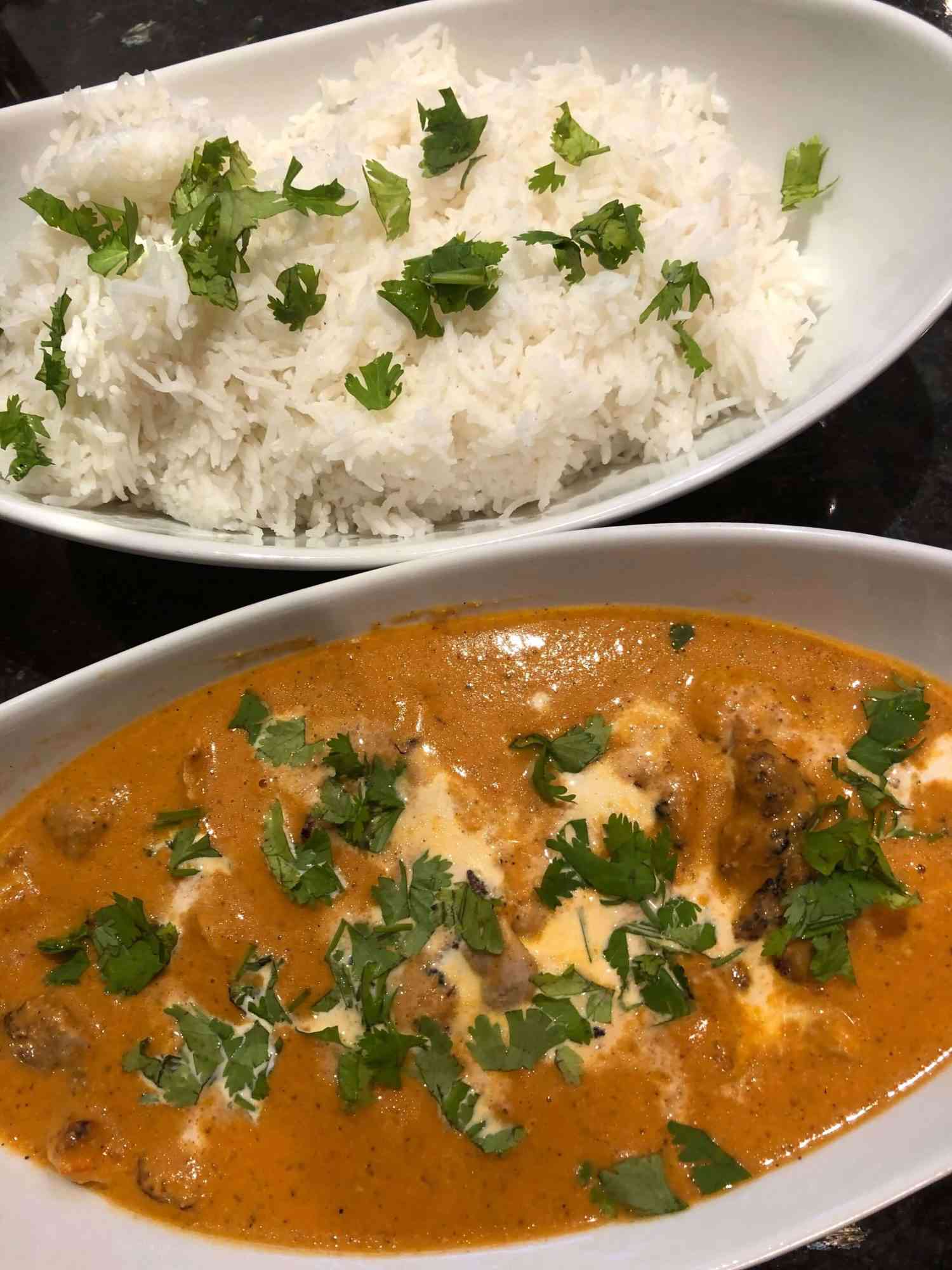 butter chicken in a serving bowl with rice alongside