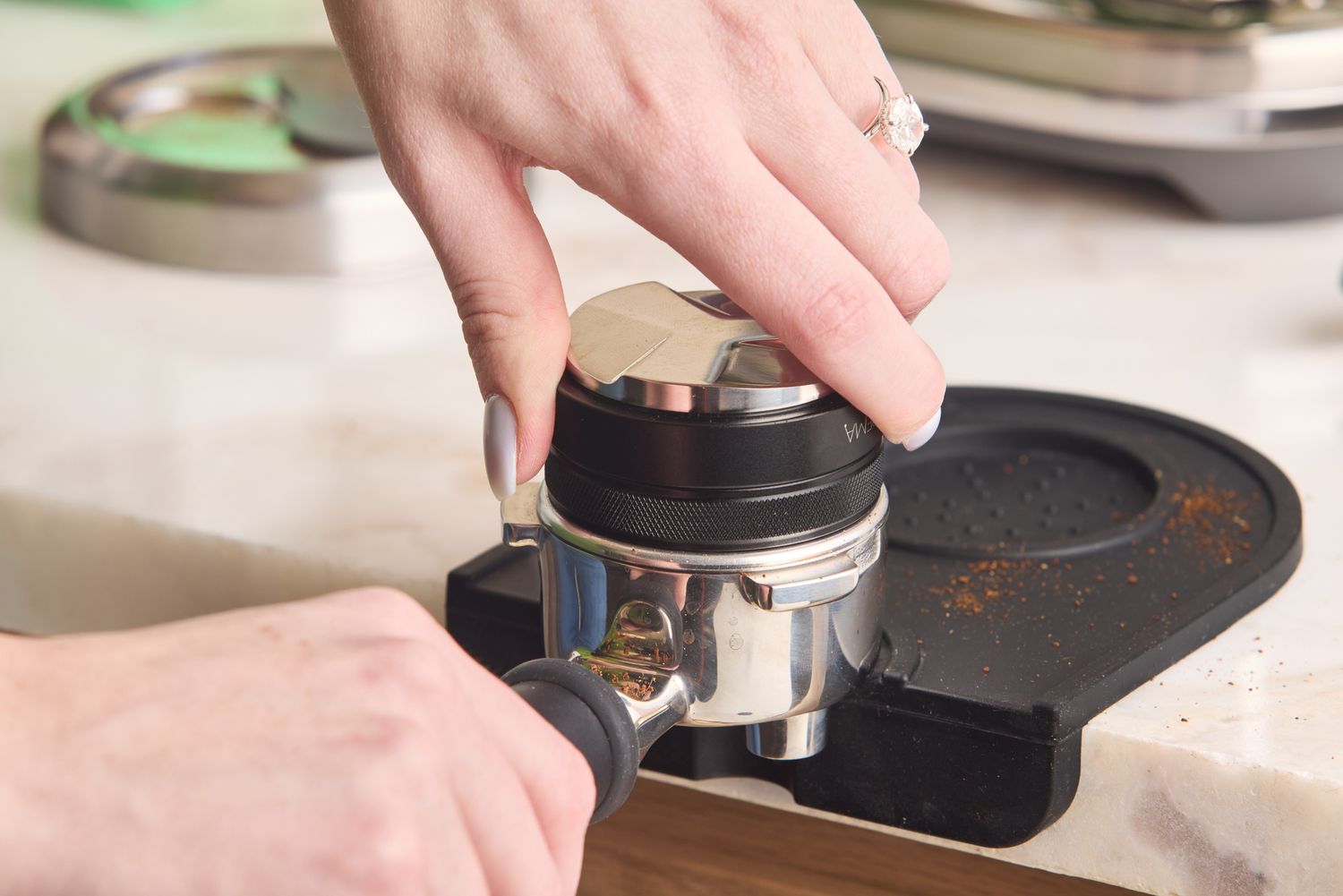 A person using a tamper to level grounds in a portafilter. 