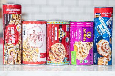 An assortment of canned cinnamon roll products from different brands lined up on a countertop