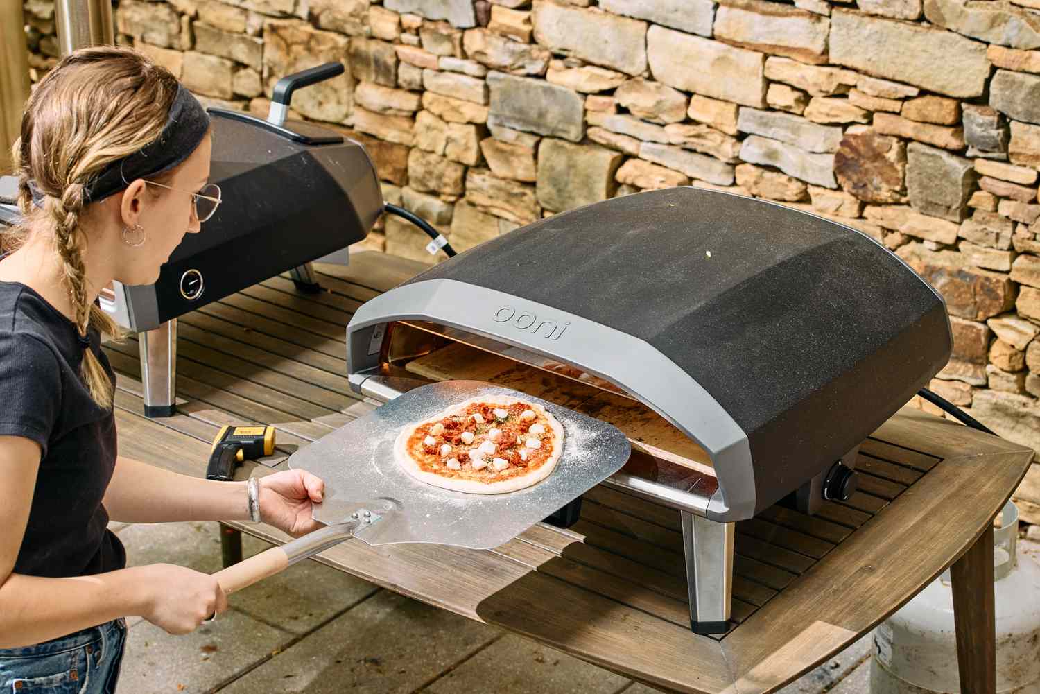A person cooks a pizza in the Ooni Koda 2 Pro Gas-Powered Pizza Oven