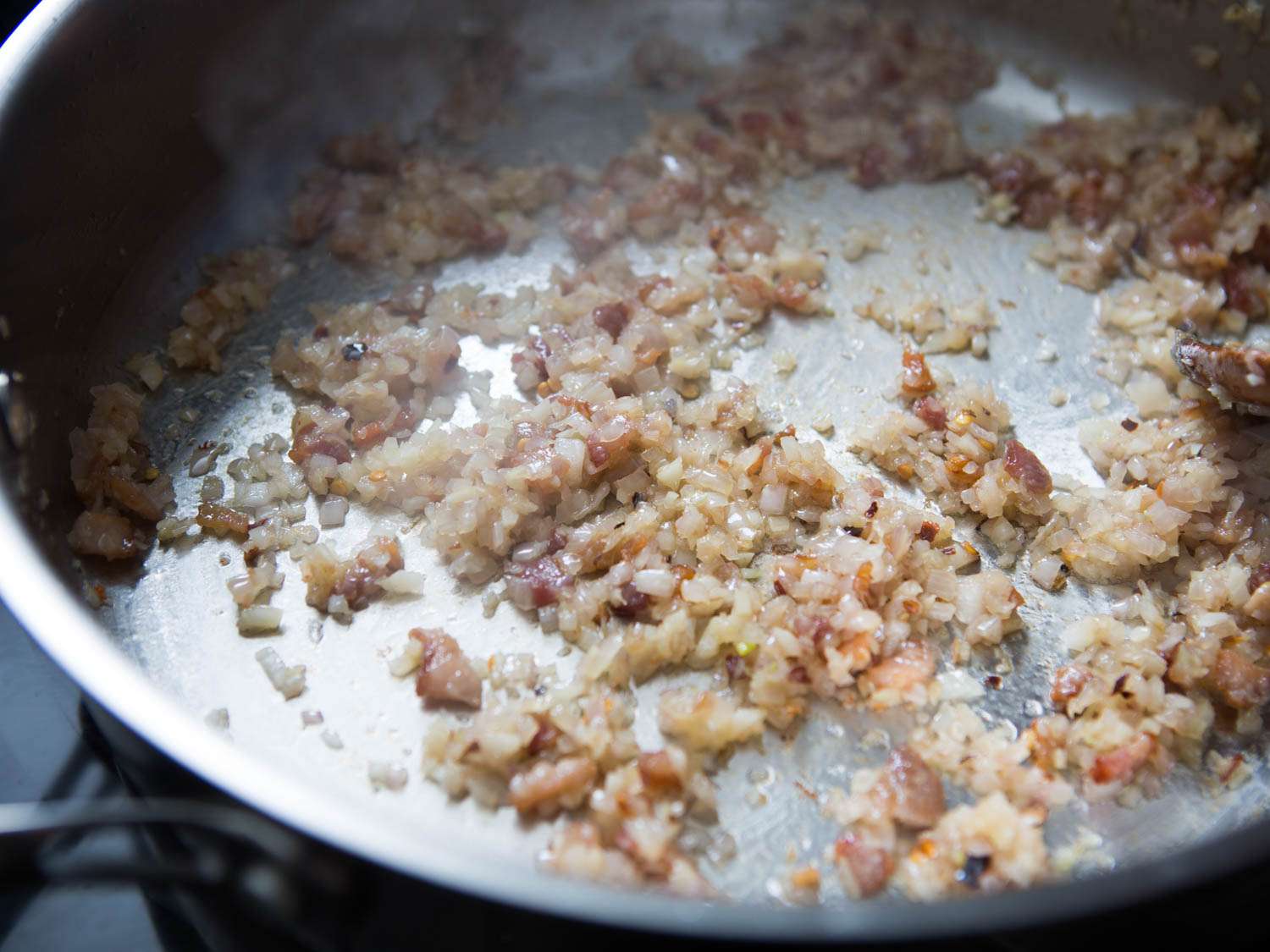 Shallots, garlic, and red pepper flakes softened in a stainless steel pan