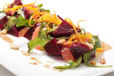 Roasted beet and citrus salad with arugula and pine nuts plated 