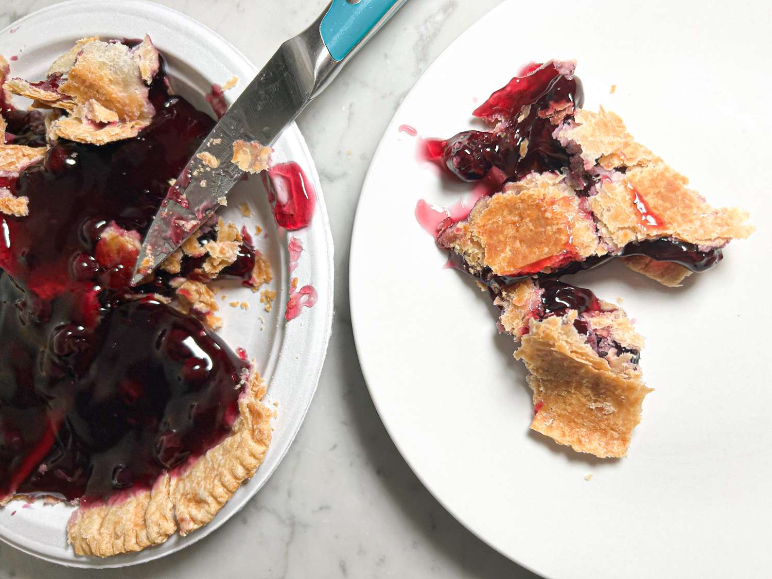 Slices of berry pie on a plate with a knife and crumbs on the side