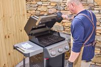 A person lifting the lid of the Weber Spirit E-310 Gas Grill