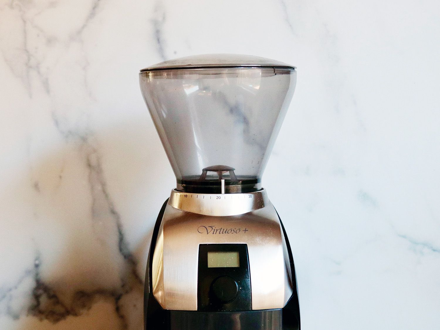 the top half of a coffee grinder framed against a white marble background