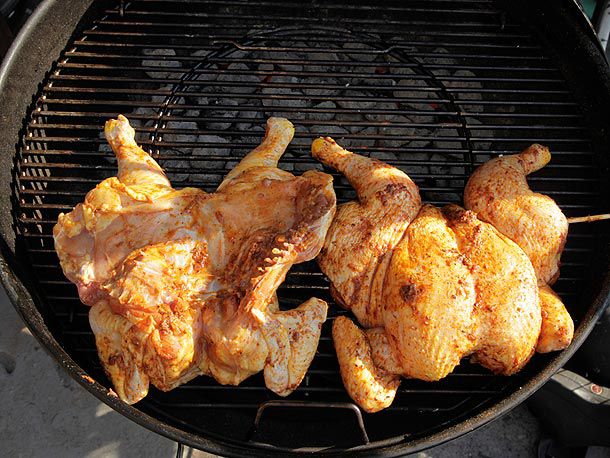 Two butterflied chickens on a grill, one with the breast facing up and the other turned so the breast is facing down.