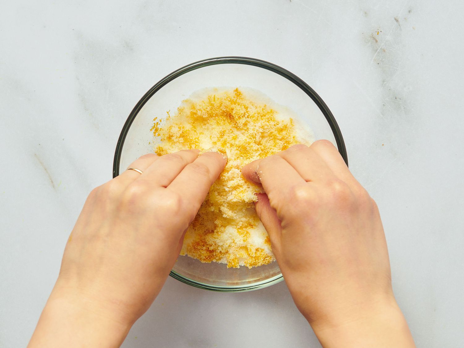 Two hands mixing lemon zest and sugar together