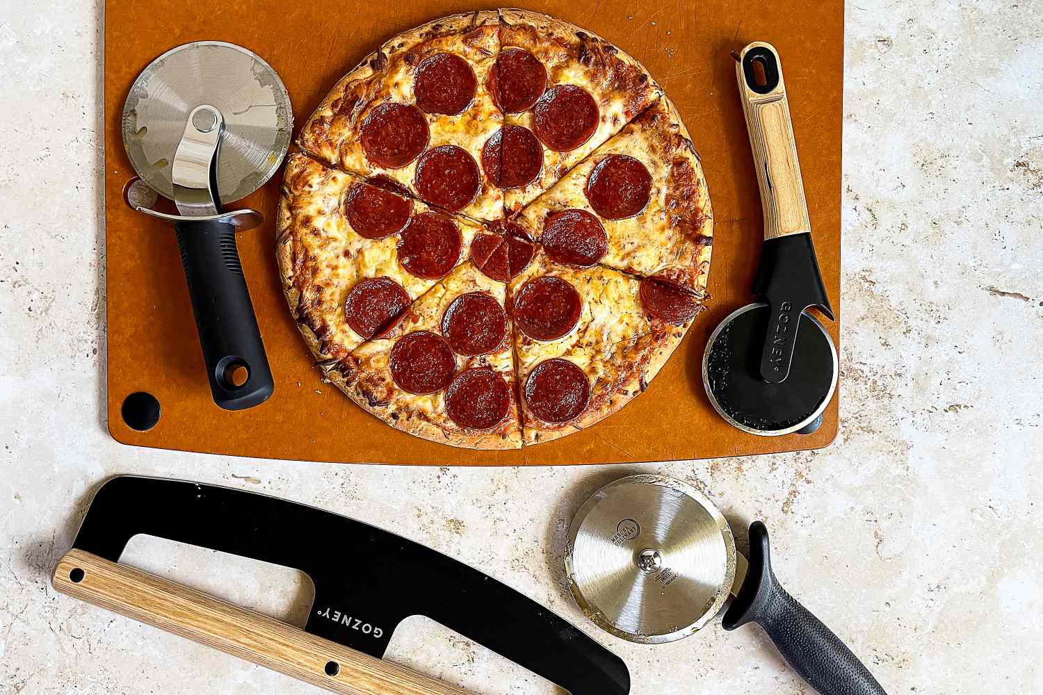 Pepperoni pizza on a board surrounded by pizza cutters