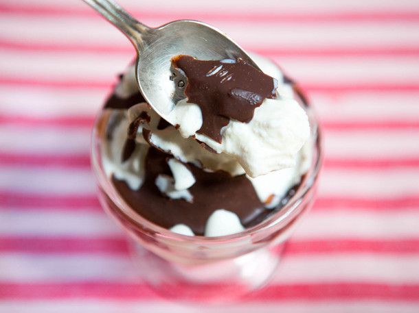Author holding a spoonful of vanilla ice cream covered with chocolate dip.