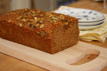 A loaf of pumpkin tea cake on a wood cutting board. 