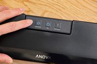 A person presses a button on the Anova Precision Sous Vide Vacuum Sealer