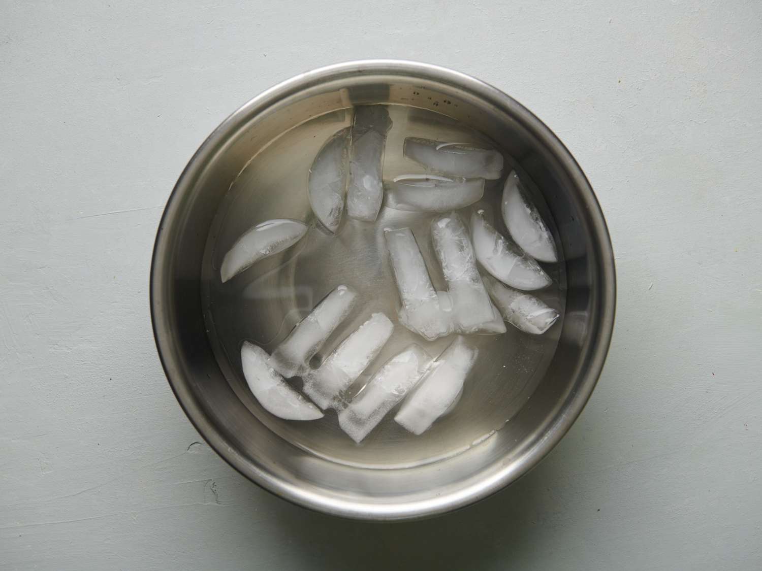 A metal bowl holding ice suspended in water.