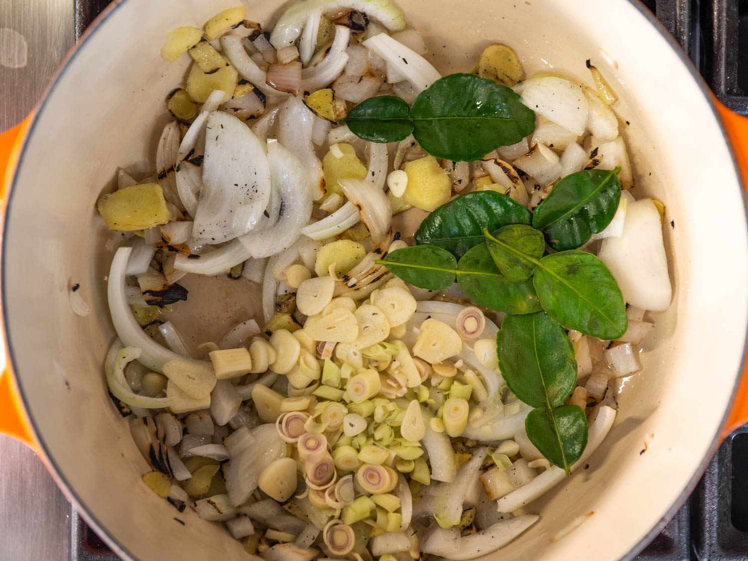 Sauteing lemongrass, makrut lime leaves, onions, garlic, and ginger for khao piak sen broth.