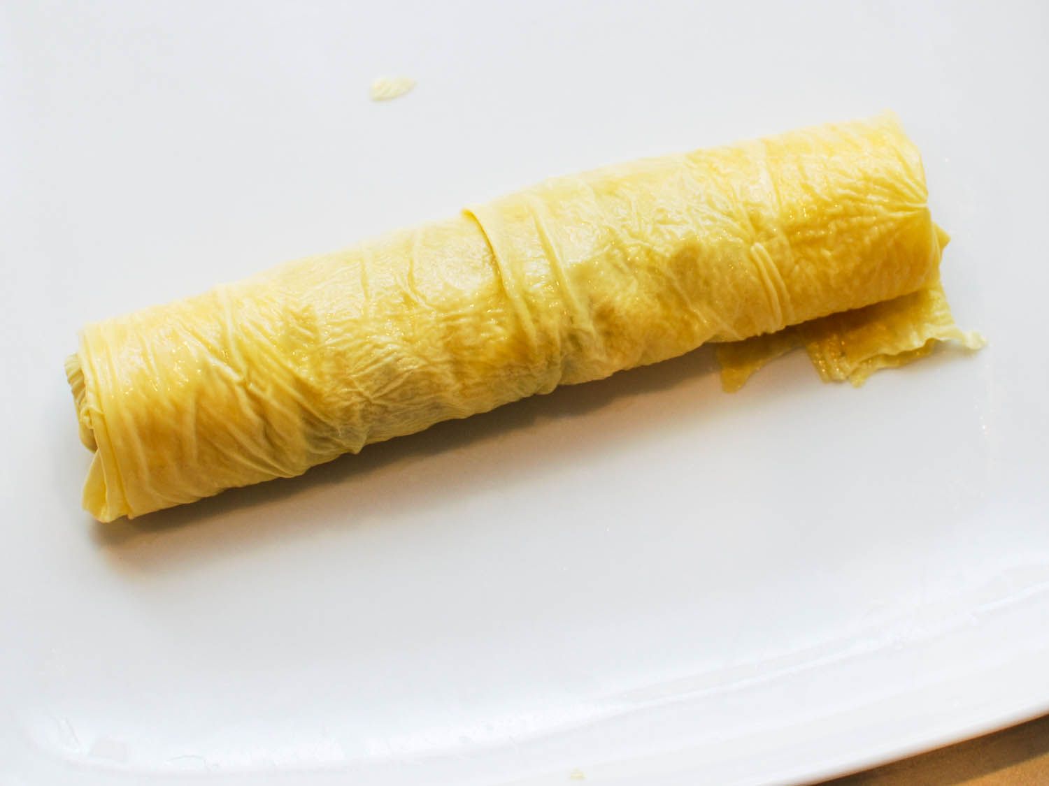 The bean curd sheet is rolled tightly around the filling.