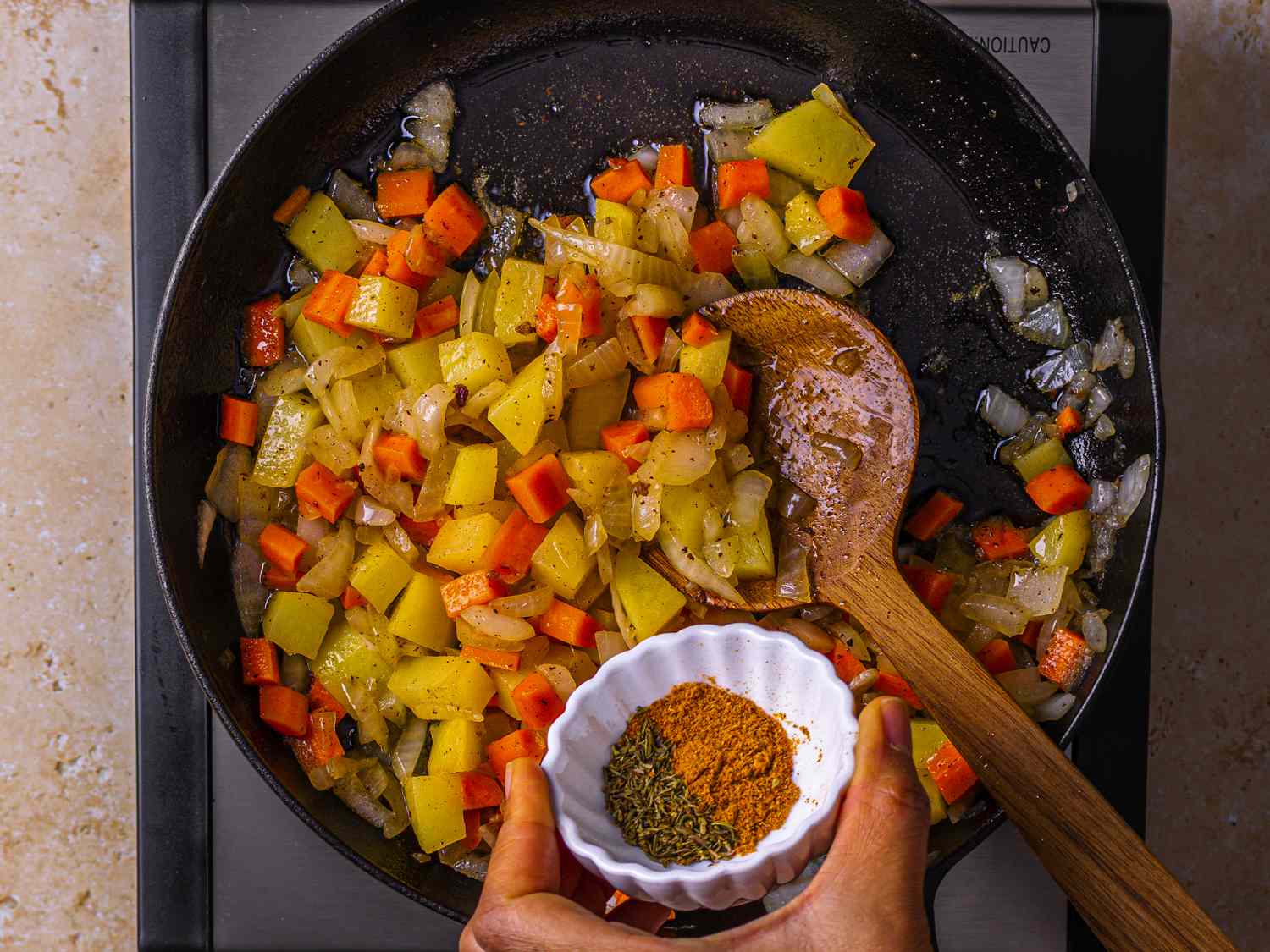 Chopped vegetables cooking with spices in a skillet.
