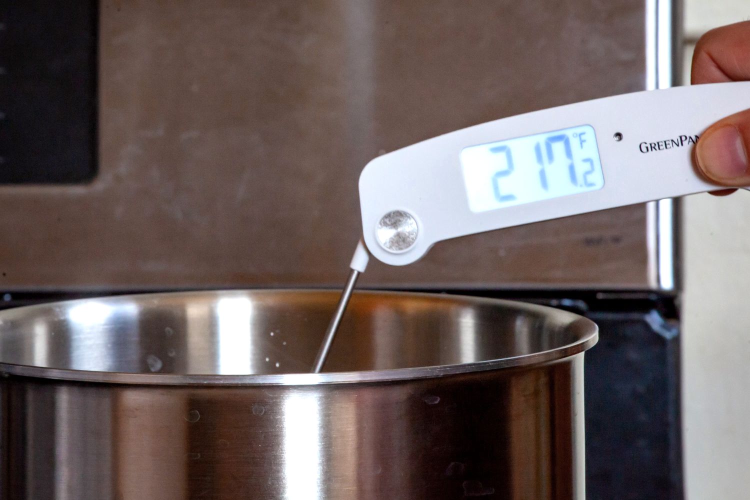 A thermometer being using to take the temperature of boiling water.