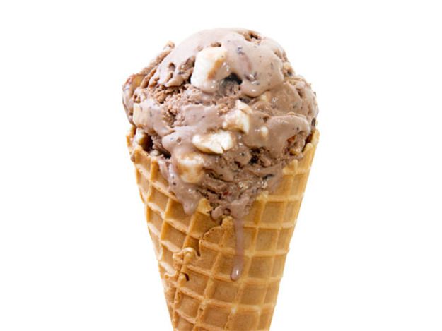 A waffle cone holding a scoop of homemade rocky road ice cream.