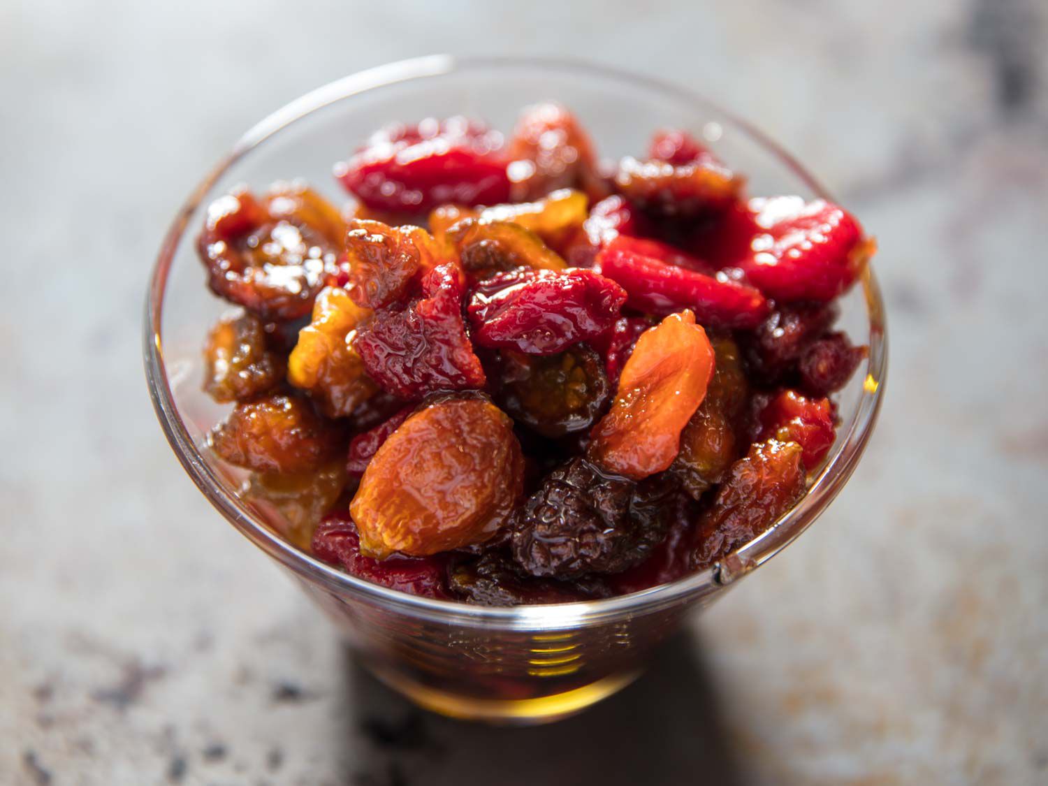 A glass bowl filled with oven-dried tomatoes that look like raisins.