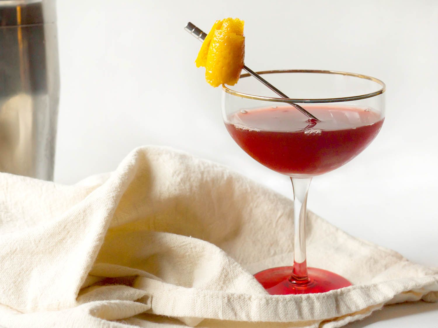 A Cranberry Especial cocktail served in a coupe glass with skewer lemon peel,