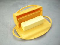 yellow butterie dish with lid opened at hinge and stick of butter inside