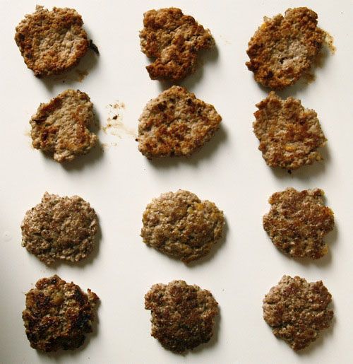 Twelve cooked turkey patties resting on a cutting board.