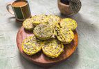 Wooden platter of egg bites, with one cut open. On a stone surface, with coffee and a small plant in the background