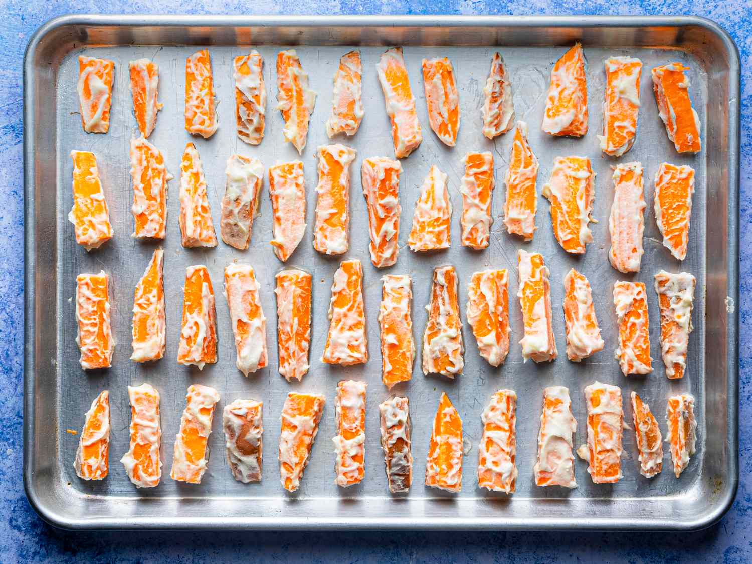 Sweet potato pieces coated with batter arranged on a baking tray