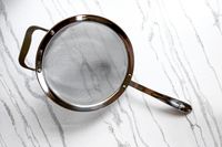 All-Clad Stainless-Steel Strainer, Set of 3 with a metal handle and rim on a marble surface