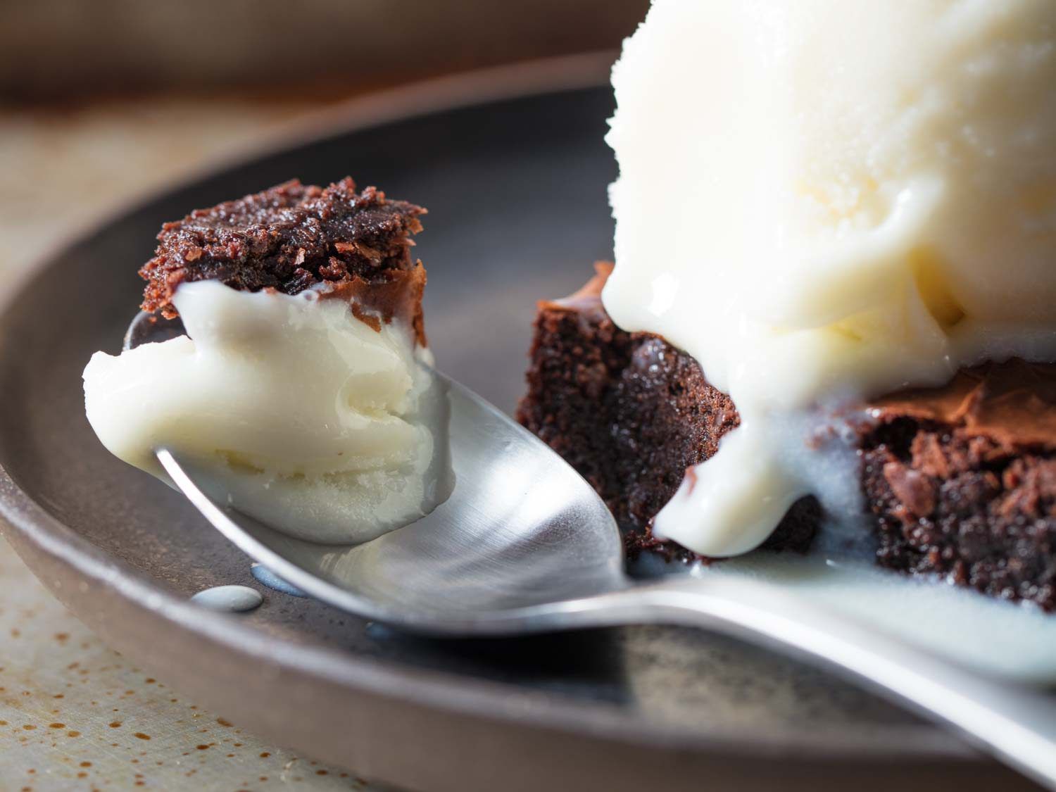 Close up of ice milk and a chunk of brownie bite on a spoon.