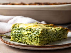 A slice of spinach lasagna, shot from the side so that all of the layers are visible.