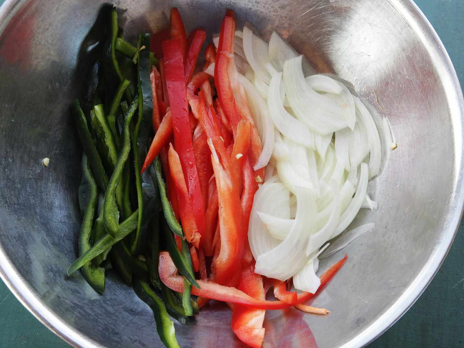 Bowl filled with sliced poblano pepper, red pepper, and onion