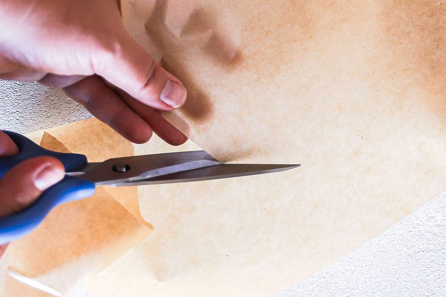A hand uses Misen scissors to cut kraft paper
